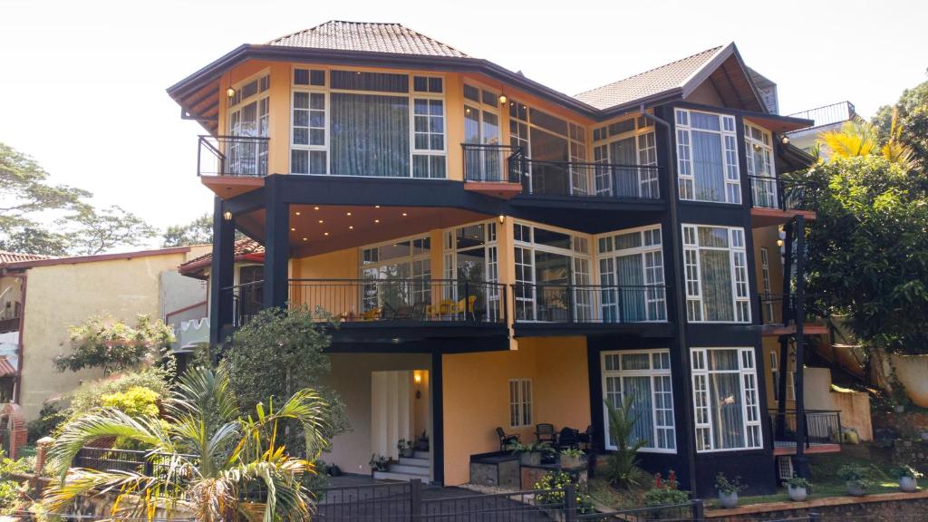 a large yellow house with balconies and trees at Roberosia - Holiday Home in Kandy