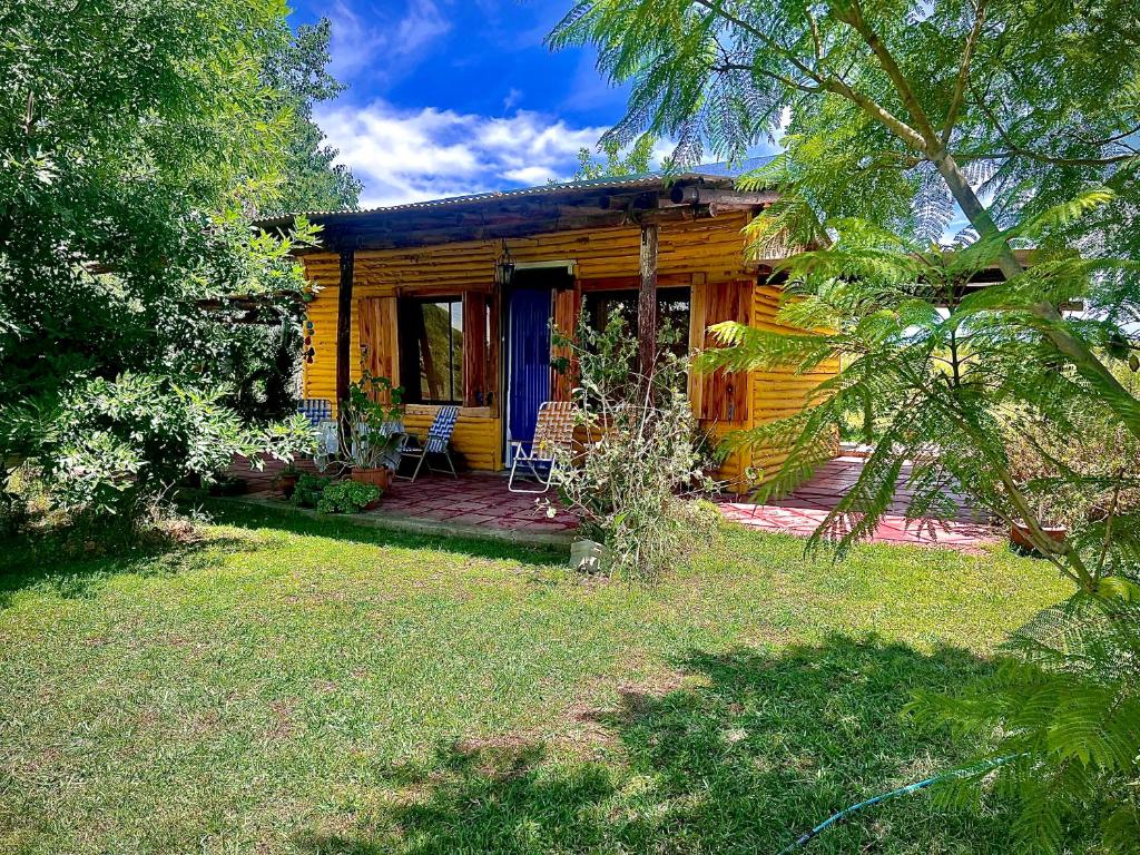 a wooden house with a porch and a yard at CABAÑA LA BOHEMIA in Colonia Hughes