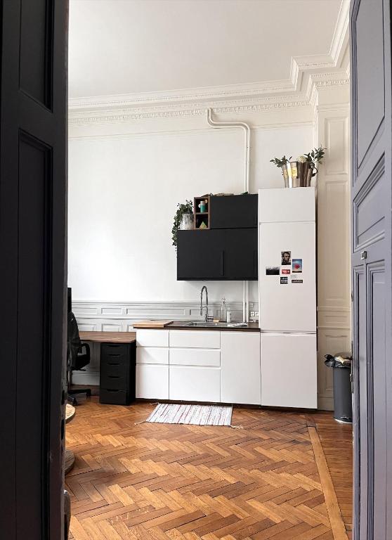 a kitchen with white cabinets and a wooden floor at Appartement typique Lillois in Lille