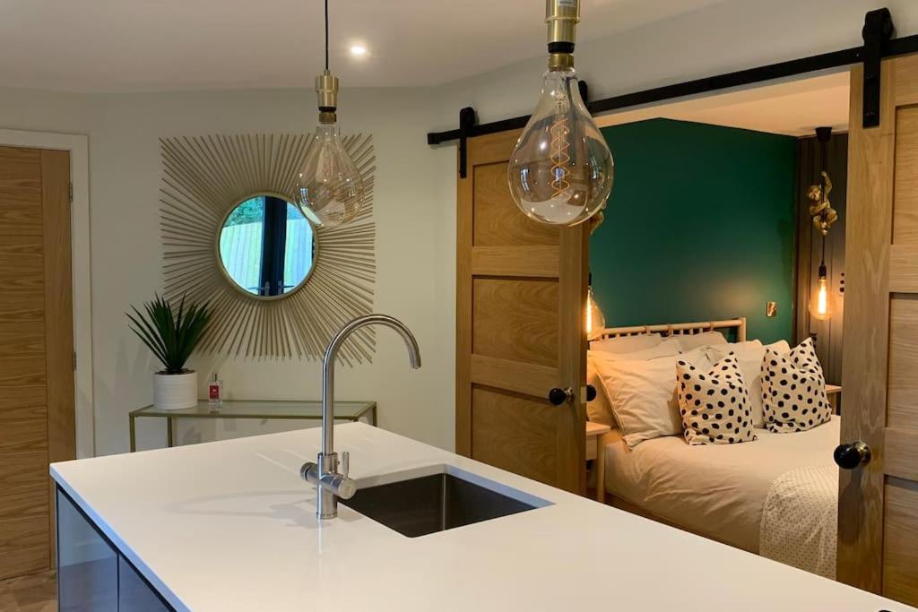a kitchen with a sink and a bedroom with a bed at Parkside Lodge - Luxury Coastal Hideaway for Two in Brixham