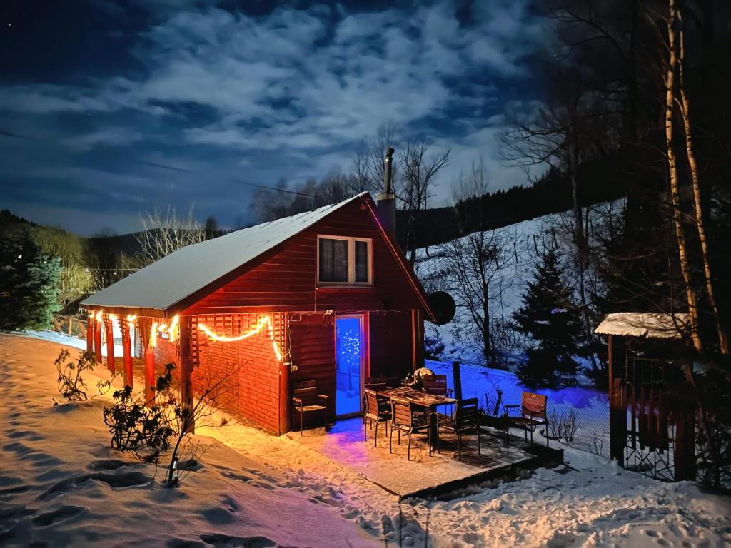 a cabin with christmas lights on it in the snow at Chata Ignasia pod Śnieżnikiem 1 na działce in Stronie Śląskie