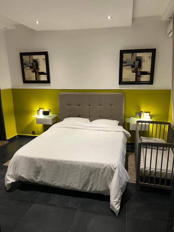 um quarto com uma grande cama branca com paredes amarelas em Meublé Nord Foire Dakar em Dakar