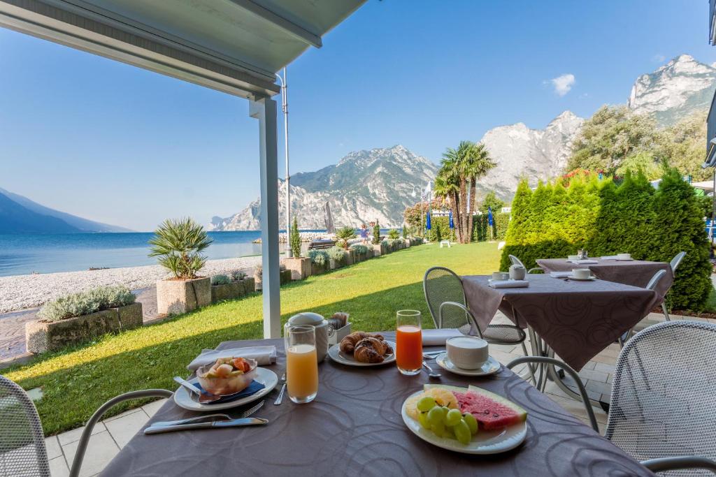 una mesa con comida y vistas al agua en Hotel Lido Blu - Surf & Bike, en Nago-Torbole