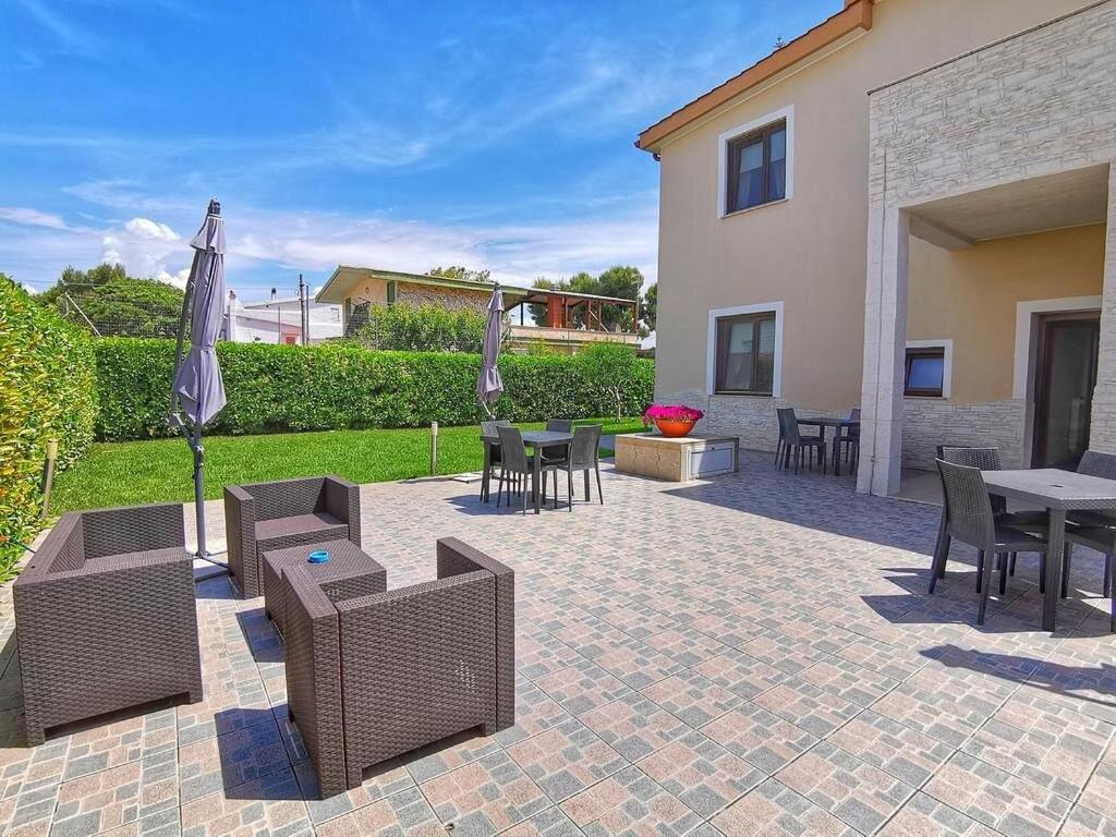 un patio con tavoli, sedie e ombrellone di Dimora Mariù - Casa Vacanze a Taranto