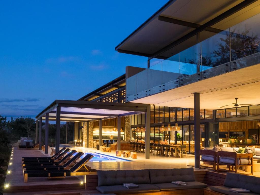 a large glass house with a swimming pool at night at Kruger Lodge Mjejane in Hectorspruit