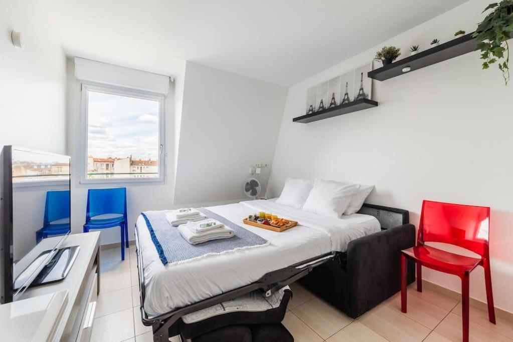 1 dormitorio con 1 cama y 2 sillas azules en Studio Socrate, en Montrouge