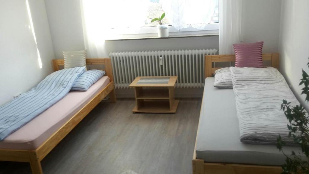 um quarto com duas camas e uma mesa e uma janela em Otthonos Szállás em Stuttgart