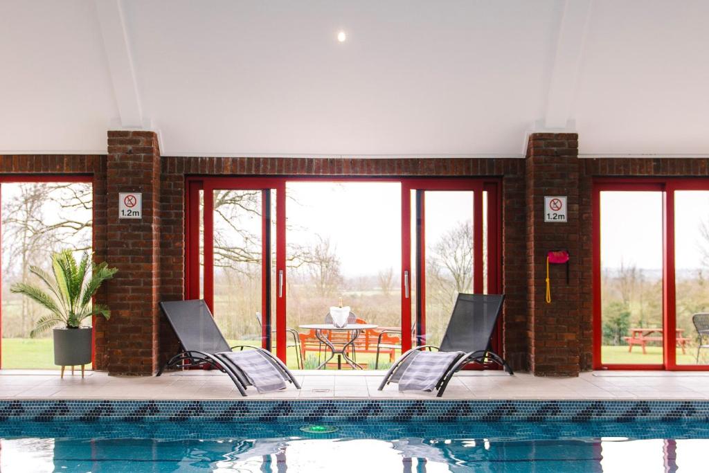 una piscina con sillas, una mesa y ventanas en Cricklade House Hotel, Sure Hotel Collection by Best Western, en Cricklade
