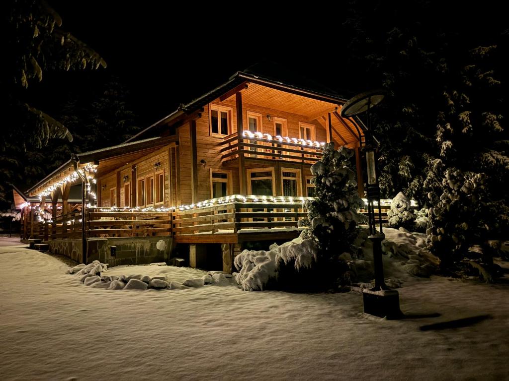 a log cabin with christmas lights on it in the snow at Orion in Borzont