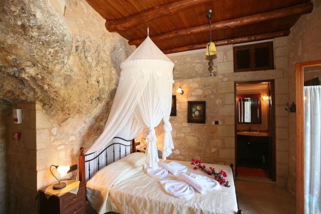 a bedroom with a bed in a stone wall at Luxurious stone cave with pool and sea view in Kissamos