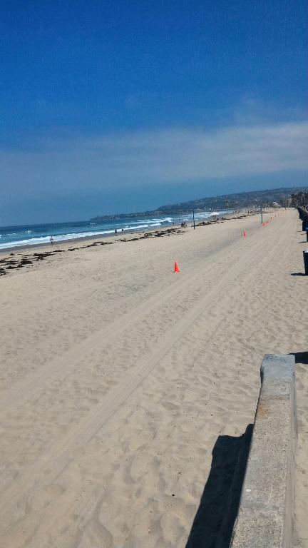 uma praia arenosa com uma cerca e o oceano em El CARMEL em San Diego