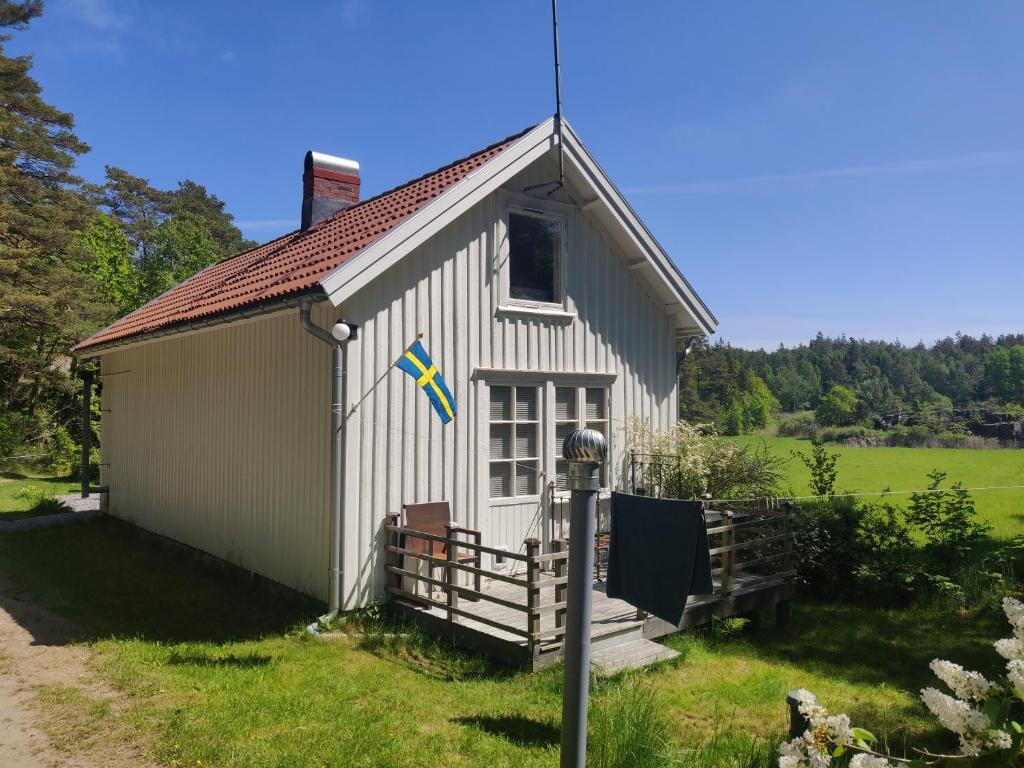 un pequeño edificio blanco con una bandera en él en 19th-century cottage on the Swedish West Coast, en Fjällbacka