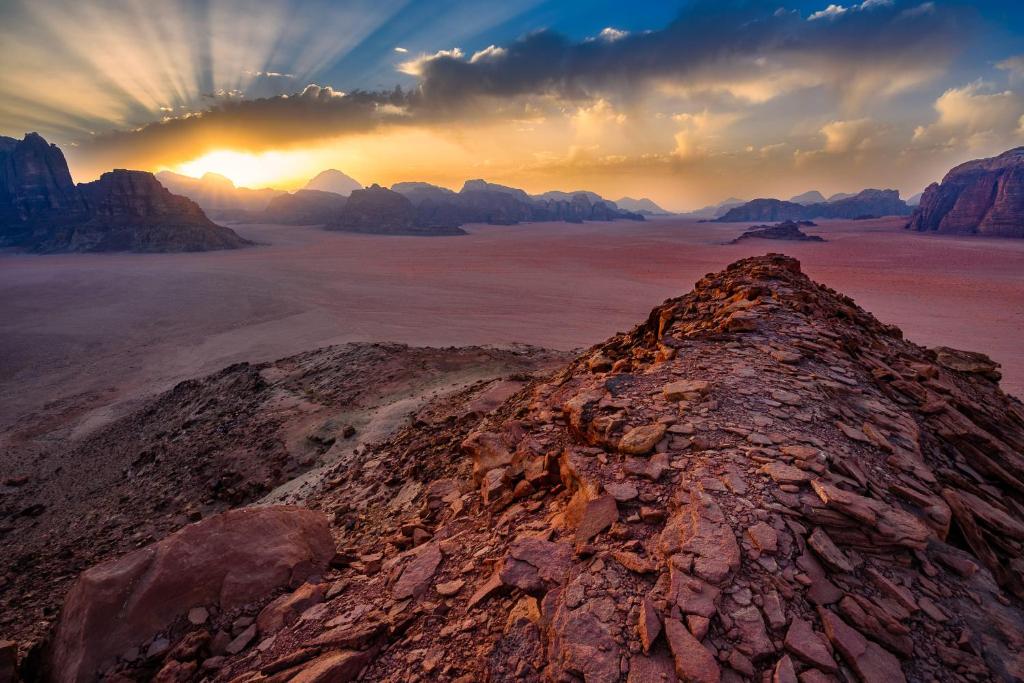 Blick auf einen Berg mit Sonnenuntergang über der Wüste in der Unterkunft Rum Gonesh Luxury Camp in Wadi Rum