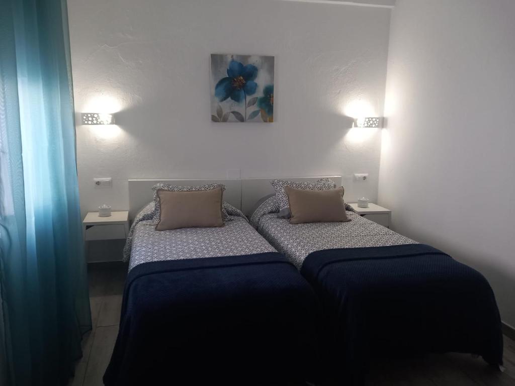 Dormitorio pequeño con 2 camas y 2 lámparas en Casa Patio Paraíso, en Vejer de la Frontera