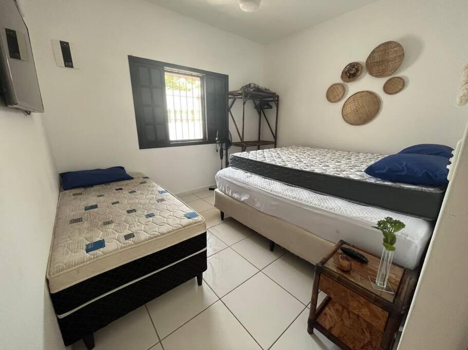 a room with two beds and a table in it at Morada do Zinho - Piscina, churrasqueira, lareira e 250 metros da praia in Itanhaém