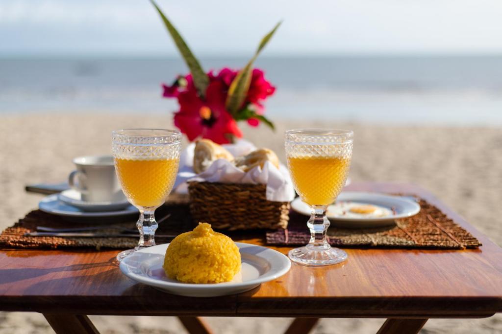 uma mesa com dois copos de sumo de laranja e alguma comida em Casa PESQUEIRA Preá - Frente Mar! em Praia do Preá