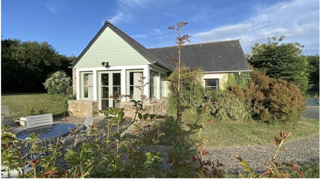 une petite maison blanche avec un banc dans la cour dans l'établissement LE COURTIL : Charmante maison Bretonne, à Saint-Alban
