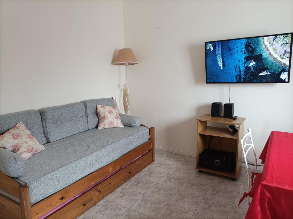 uma sala de estar com um sofá e uma televisão de ecrã plano em Ale Belgrano em Mar del Plata