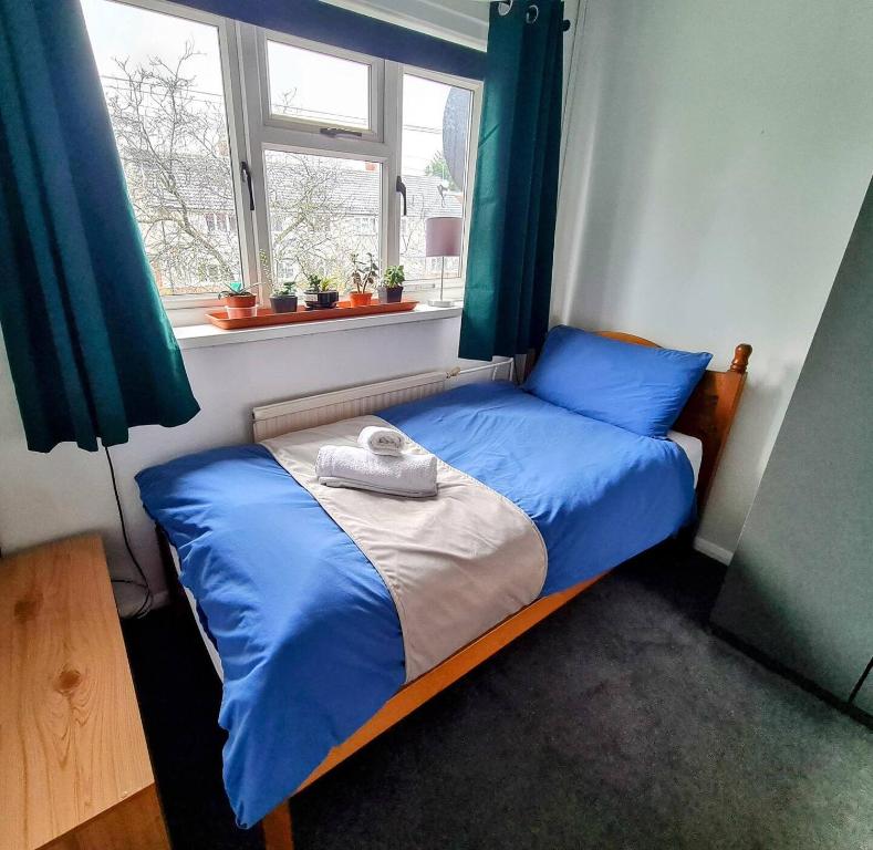 uma cama com lençóis azuis num quarto com uma janela em Spacious Rooms close to Aylesbury Centre - Free Fast WiFi em Buckinghamshire