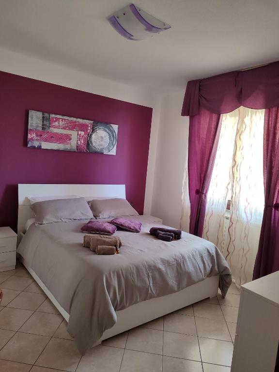 1 dormitorio con 1 cama grande y paredes moradas en Dario's house en Sassari