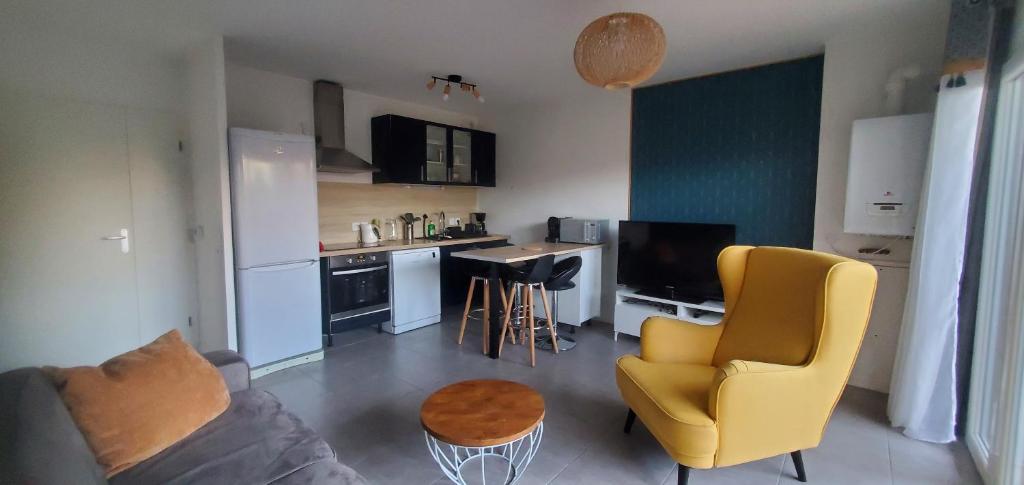 a living room with a yellow chair and a kitchen at T2 au cœur du bassin d'arcachon in Gujan-Mestras