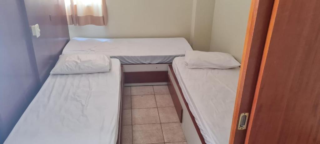 a small room with two beds and a door at Cobertura Parque das Aguas in Caldas Novas