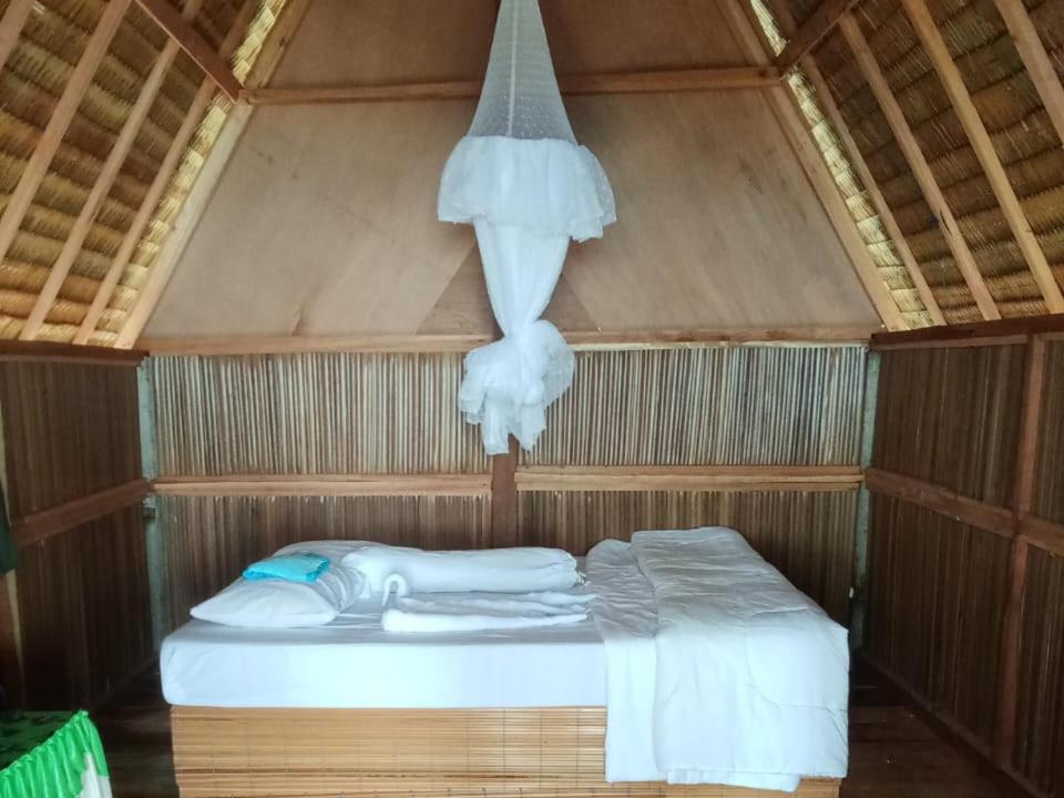 a bed in a wooden room with a net at Or Mandira Guest House in Fam