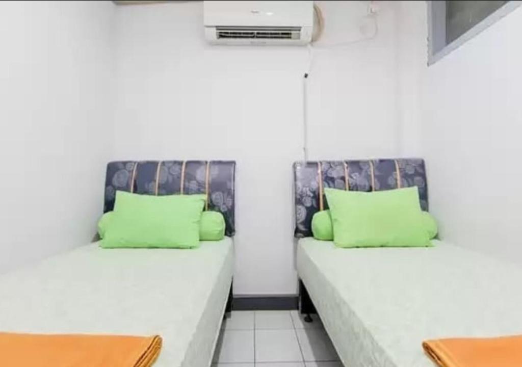 2 letti in una camera con cuscini verdi di Barrel Homestay, 4 mins Mentawai fast ferry, food, drink, sleep, transport by nginapdipadang a Padang