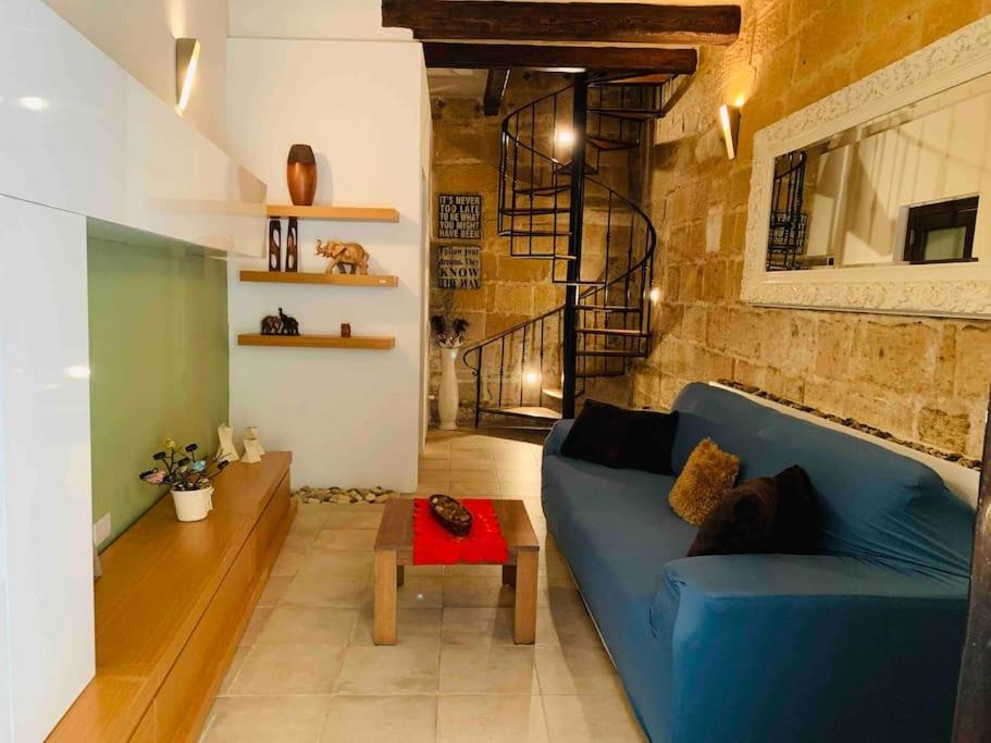 - un salon avec un canapé bleu et une table dans l'établissement Authentic House of Character, à Il-Birgu