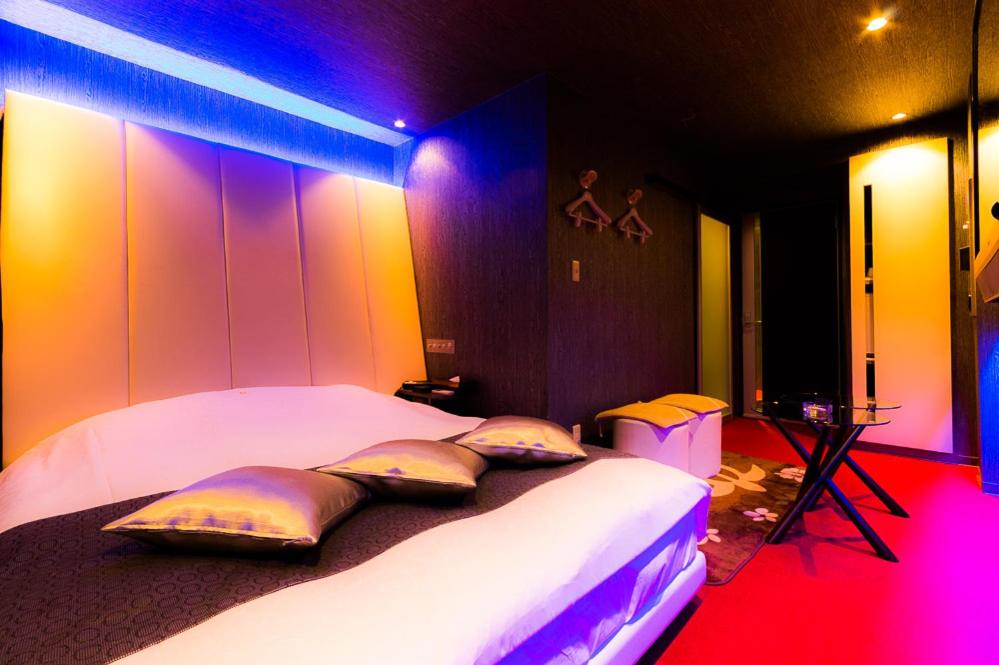 two beds in a room with purple and pink lights at ホテルR -Adult only- in Gotemba