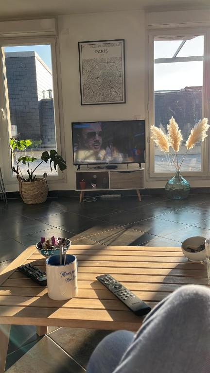 - un salon avec une télévision et une table basse dans l'établissement Appartement avec roof top, à Saint-Brice-sous-Forêt
