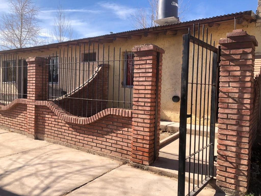 einen Steinzaun mit einem Tor vor einem Gebäude in der Unterkunft Cuarta División Apartments in Malargüe