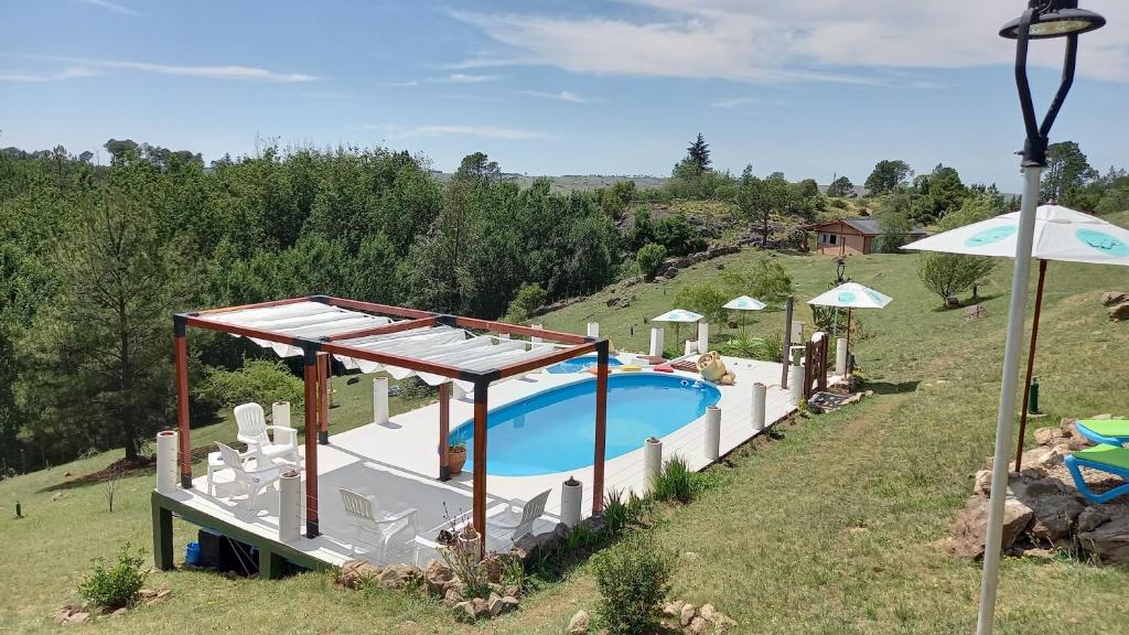 an image of a swimming pool in a field at Cabañas & Suites "No es Fácil" in Villa Yacanto