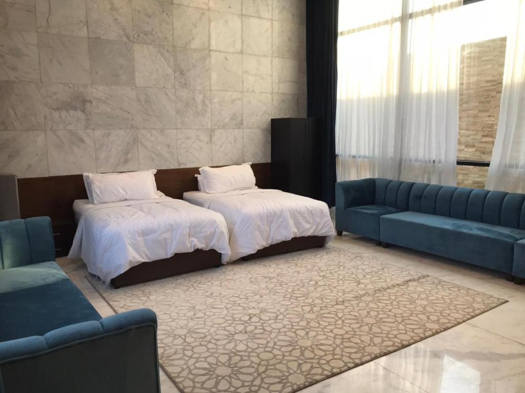 um quarto com uma cama e um sofá azul em SAAF RESORT em Al Ghuţghuţ
