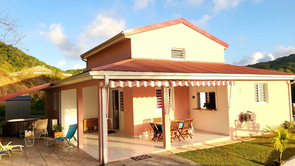 Cette maison blanche dispose d'une terrasse et d'une table. dans l'établissement Maison Indép, Spa, Mer, Jardin, Bien-être, à Les Trois-Îlets