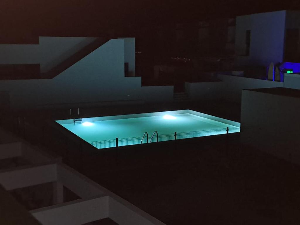 a swimming pool with lights in a dark room at Casa Fuerteremote - new and modern house with office in Corralejo in La Oliva