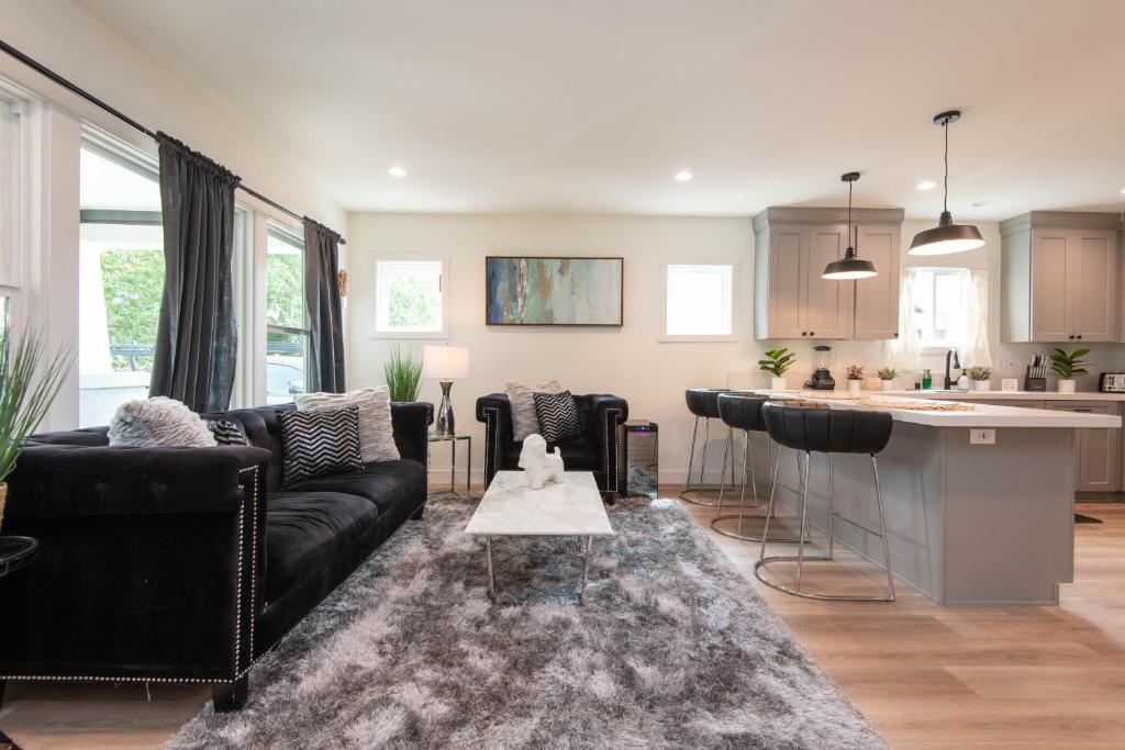 a living room with a black couch and a kitchen at Epic House in Atwater Village in Glendale