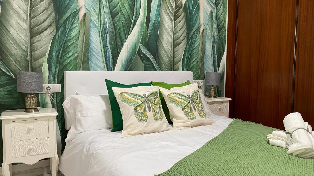 Schlafzimmer mit einem Bett mit grünen und weißen Kissen in der Unterkunft AljaLux Sevilla Bormujos in Bormujos