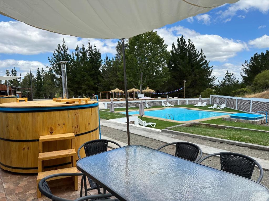 a table and chairs with an umbrella and a pool at Complejo bosque escondido in Quillón