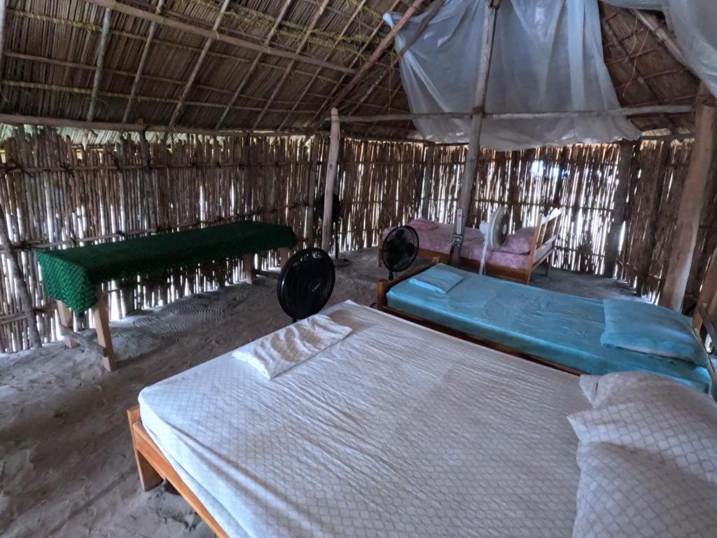 a bedroom with two beds and an umbrella at Cabaña tradiconal en isla Perro chico San blas in Wagsalatupo Grande