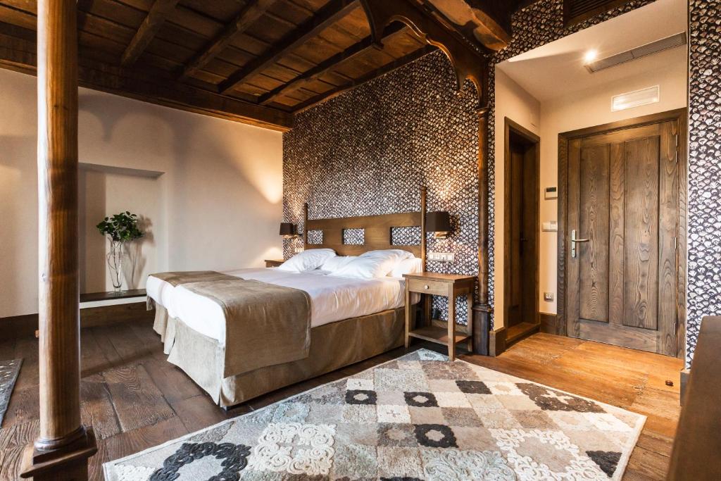 a bedroom with a large bed and a wooden wall at Pazo da Pena Manzaneda in Manzaneda