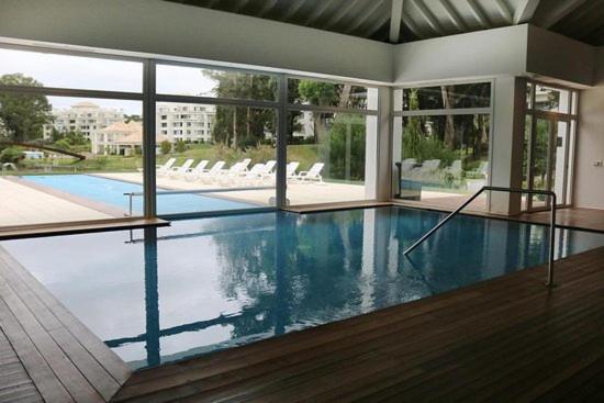 a large swimming pool in a building with a large window at Green Park Propietario in Punta del Este