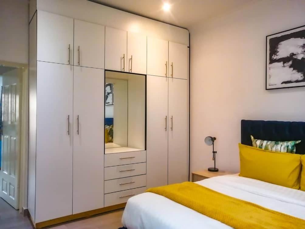 sypialnia z białymi szafkami i żółtym łóżkiem w obiekcie Crystal Apartments Area 43 w mieście Lilongwe