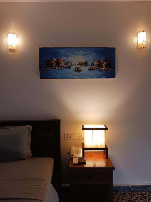 a bedroom with a bed and a desk with a lamp at Andy's Place in Siem Reap