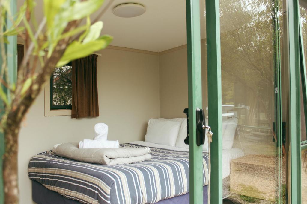 - une chambre avec un lit et une porte coulissante en verre dans l'établissement The Barn Cabins & Camp, à Marahau