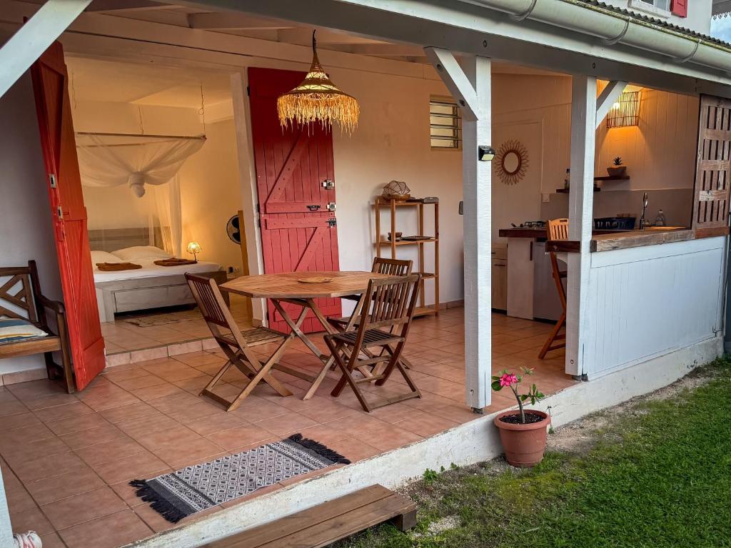 a patio with a table and chairs and a kitchen at Gîte Ti Carbet - Vue mer in Grand-Bourg