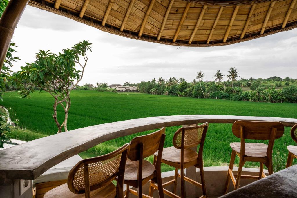 - une terrasse couverte avec des chaises et une vue sur un champ dans l'établissement Shanti Boutique Retreat, à Tanah Lot