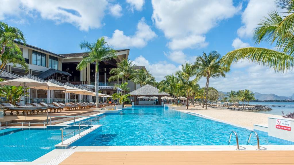 a pool at the resort with palm trees and a beach at InterContinental Mauritius Resort Balaclava Fort, an IHG Hotel in Balaclava