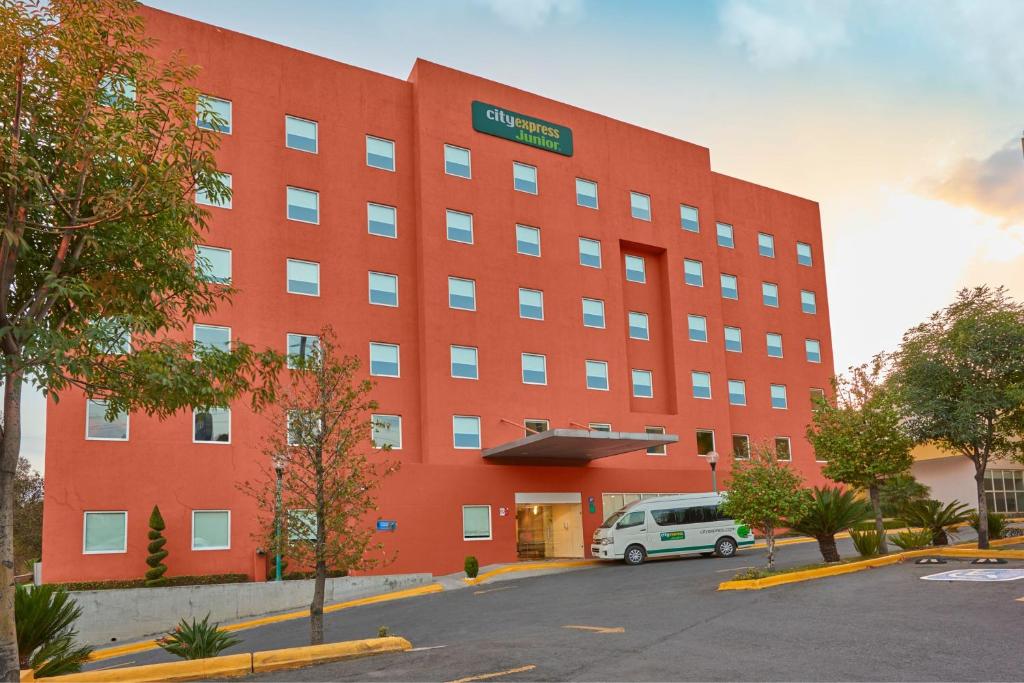 a large red building with a van parked in front of it at City Express Junior by Marriott Puebla FINSA in Puebla