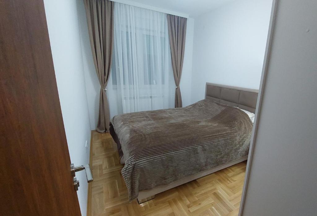 um pequeno quarto com uma cama e piso em madeira em Apartman Veljković Zapadni Kej em Pirot